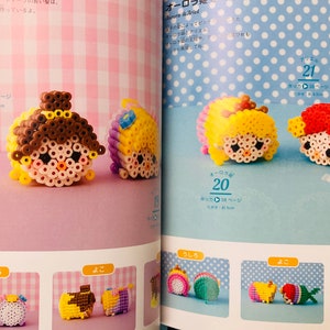 May include: A book with instructions on how to make bead sprites of Disney princesses. The book shows images of completed bead sprites of Belle, Cinderella, Rapunzel, and Ariel. The book is open to a page with the title "Aurora & Ariel".