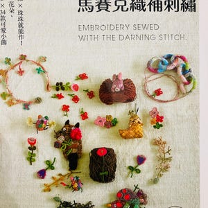 Può includere: Copertina di un libro con vari progetti di ricamo fatti a mano, tra cui piccole figure di animali, fiori e altri oggetti decorativi. Il testo sulla copertina recita "Ricamo cucito con il punto di rammendo".