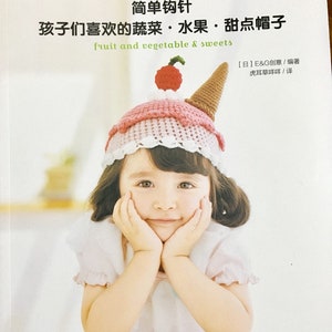 Pode incluir: Uma capa de livro com uma menina pequena usando um chapéu de crochê em forma de cone de sorvete. O título do livro é "Crochê simples: Vegetais, frutas e doces favoritos das crianças" em chinês e inglês. A capa do livro é branca com um fundo rosa claro.