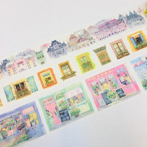 May include: Decorative washi tape featuring a watercolor design of European buildings, windows, and shops. The tape includes images of storefronts with the word "Summer" and "Mini Shop" on the tape. The tape is on a white background.