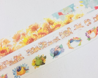 May include: Washi tape rolls with diverse designs. One roll features sunflowers, another Shiba Inu dogs, and others depict birds with floral details. The tape has a white background and colourful illustrations.