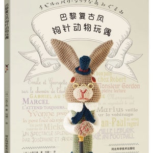 May include: A book cover featuring a crocheted rabbit wearing a top hat, glasses, and a suit. The book title is in Chinese characters, with additional text in Japanese and French. The background is a cream color with French words.