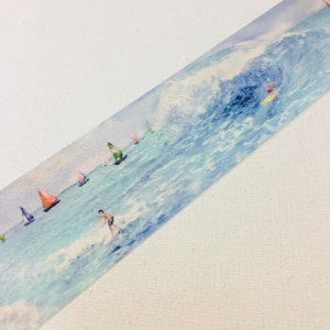 May include: Watercolour washi tape featuring a blue ocean scene with sailboats and a surfer. The tape has a white background and a light blue watercolour wash.