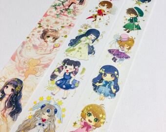 May include: A roll of decorative washi tape featuring a repeating pattern of anime-style characters in colourful outfits, interspersed with gold foil star constellations, floral motifs, and celestial elements printed on a white background.