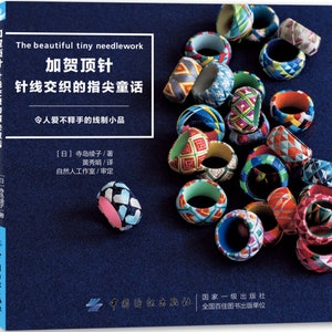 May include: A book cover titled The beautiful tiny needlework featuring Chinese text and a collection of colorful, intricately woven fabric rings in various geometric patterns, displayed against a dark blue background with a visible spine.