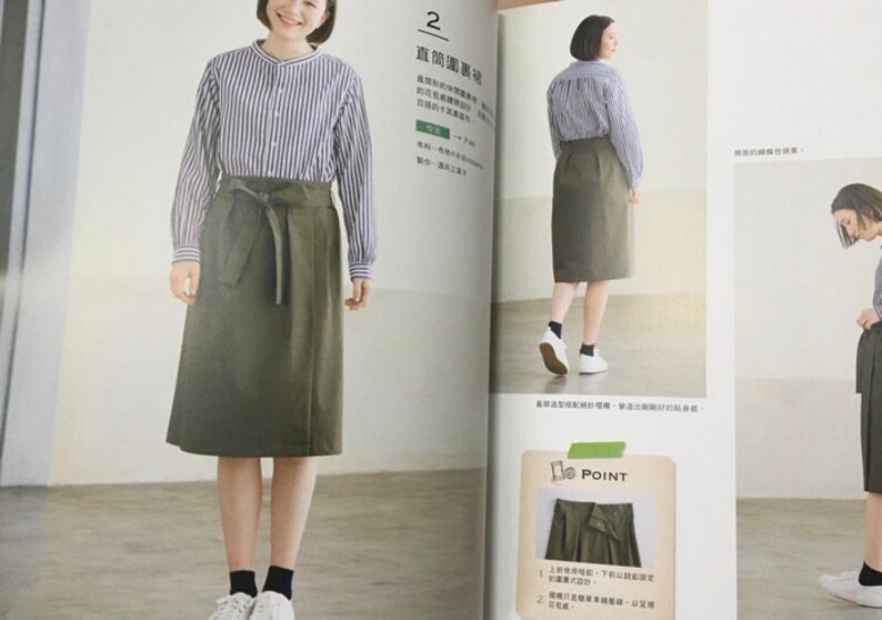 May include: A woman wearing a long-sleeved, blue and white striped shirt and an olive green skirt with a tie waist. The skirt falls to the mid-calf. The woman is wearing white sneakers and black socks. The image is from a fashion magazine.