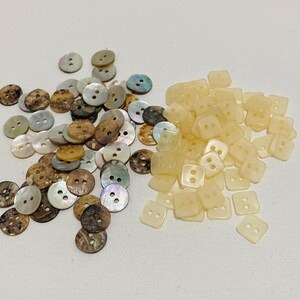 May include: A selection of buttons in different shapes and colours. Round buttons in shades of brown, tan, and iridescent white are next to square, light yellow buttons. These buttons are suitable for sewing and craft projects.