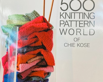 May include: A book titled "500 Knitting Pattern World of Chie Kose" with a stack of colorful knitted fabric swatches in a glass jar and two wooden knitting needles.