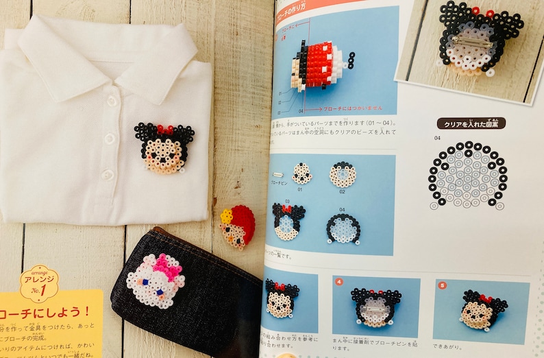 May include: A book with instructions on how to make beaded characters. The book shows a variety of characters, including Mickey Mouse, Minnie Mouse, and other Disney characters. The book also includes a close-up of a beaded character being made.