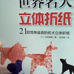 May include: A book cover featuring the title "World Famous Dogs 3D Origami" in large black and red characters. The cover displays origami dog figures in red and white patterns, and blue and black paper. The book is published in Chinese.