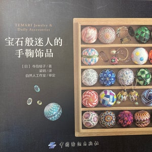 May include: A wooden box filled with colorful, hand-stitched Temari balls. The balls are arranged in rows and are decorated with various patterns and colors. The box is labeled "Temari Jewelry & Daily Accessories" and "宝石般迷人的手鞠饰品" in Japanese.