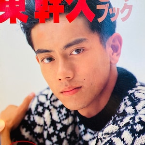 May include: A close-up portrait of a young man with dark hair wearing a black and white patterned sweater. The text "東幹久" is written in red above his head.