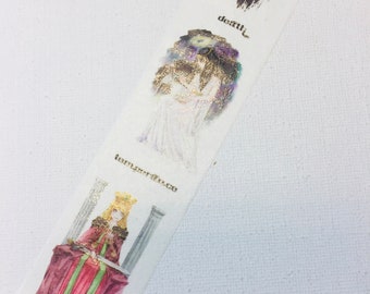 May include: A white washi tape with gold foil accents features illustrations of figures from the Major Arcana tarot deck. The figures are depicted in a watercolour style. The text "justice", "temperance", "death" is visible on the tape.