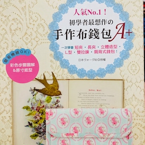 May include: A craft book with Japanese text, featuring a light blue wallet with a pink floral pattern. The book includes a gold bird and floral embellishments, with text that reads "Easy Sewing OK!" and "Popular No.1!"