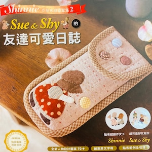 Op de afbeelding: Boekomslag met een stoffen etui met een meisjesapplicatie. De etui is beige met bruine randen en decoratieve knopen. De titel van het boek is "Sue & Shy" in het Engels en in Chinese karakters. Extra tekst bevat "Shinnie" en "Friends' Diary".