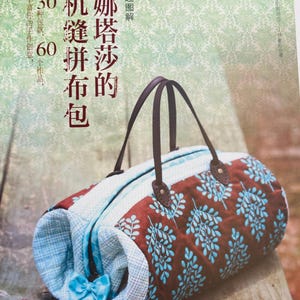 Puede incluir: Una bolsa de mano de patchwork marrón y azul con un asa de cuero marrón. La bolsa tiene un patrón de cuadros azul y blanco en un lado y una tela marrón con un patrón de hojas azules en el otro lado. La bolsa tiene un lazo azul en el lateral.