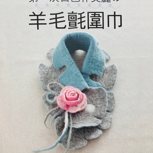 May include: A blue and grey wool felt scarf with a pink felt flower. The scarf is folded into a loop and the flower is attached to the front. The text "洗搓搓!" and "第一次自己作美麗の" is written in black above the scarf. The text "羊毛氈圍巾" is written in black below the scarf.