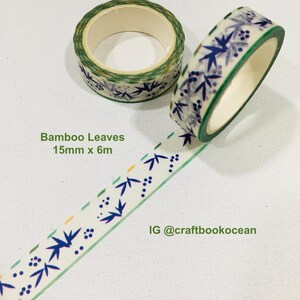 Op de afbeelding: Twee rollen washi-tape met een patroon van blauwe bamboebladeren en kleine stippen op een witte achtergrond. De tape meet 15mm x 6m en is gelabeld met Bamboo Leaves. De tekst IG @craftbookocean is ook zichtbaar op de afbeelding.