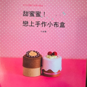 Puede incluir: Una portada de libro con fondo rosa de lunares. El título es "Sweet Sweet!" en letras negras grandes. El subtítulo es "Amor a primera vista Cajas pequeñas de tela hechas a mano" en letras negras más pequeñas. El nombre del autor es "Sugisaki Megumi" en letras negras más pequeñas. La portada presenta dos pequeñas cajas de tela, una marrón y una blanca, decoradas para parecer pasteles.