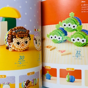 May include: A book with instructions on how to make bead sprites of popular characters, including Woody from Toy Story and an alien from Toy Story. The book includes a close-up image of a completed bead sprite of Woody and a close-up image of three completed bead sprites of aliens.