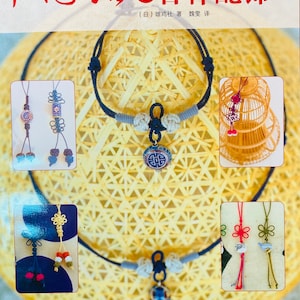 May include: A book cover with the title "Chinese Knots: Auspicious Ornaments" in Chinese characters. The cover features a variety of colorful Chinese knot designs, including a necklace, a keychain, and a birdcage ornament. The book is published by Liaoning Science and Technology Publishing House.