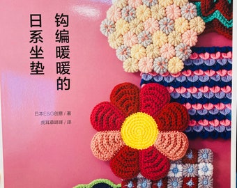Puede incluir: Una portada de libro con el título "钩编暖暖的" en caracteres chinos, que se traduce como "Crochet Calidez". La portada presenta una variedad de artículos de crochet coloridos, incluyendo flores, cuadrados y círculos.