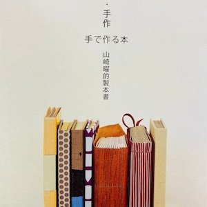 Puede incluir: Una colección de libros hechos a mano con varias cubiertas, incluyendo diseños y colores lisos. Los libros están dispuestos en fila, con texto japonés en la parte superior.