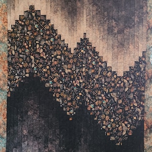 May include: A quilt with a dark background and a design of a mountain made of small squares. The squares are filled with a variety of small, metallic objects, such as gears, keys, and other trinkets. The quilt has a rustic, vintage look.