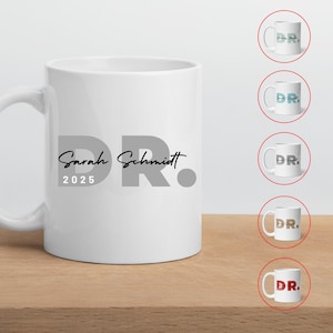 Könnte beinhalten: Weiße Keramik-Kaffeetasse mit einem grauen "DR." Design und dem Text "Sarah Schmidt 2025".