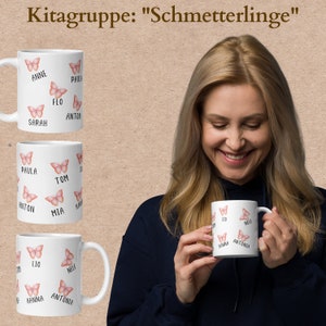 May include: White ceramic mugs with pink butterfly illustrations and names. The mugs have names like Anne, Sarah, Paula, Tom, Mia, Lio, Nele, Hanna, and Antonia. The text "Kitagruppe: Schmetterlinge" is at the top.