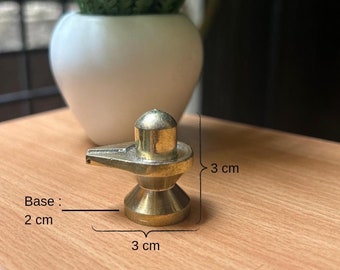Könnte beinhalten: Eine kleine, goldfarbene Shiva Lingam-Statue aus Messing mit Sockel. Die Statue ist 7,6 cm hoch und 7,6 cm breit. Der Sockel ist 5 cm breit.