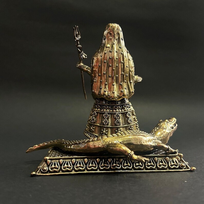K&ouml;nnte beinhalten: Bronzestatue einer verschleierten Figur, die einen Dreizack h&auml;lt und auf einem Sockel mit einem Alligator steht. Die Figur ist mit komplizierten Details verziert, und der Alligator liegt. Die Statue hat eine Vintage-&Auml;sthetik.