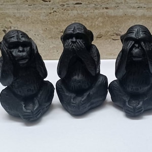 Puede incluir: Tres figuritas de mono negras, cada una cubriendo un sentido diferente: una se tapa los ojos, otra se tapa las orejas y otra se tapa la boca.
