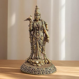 Peut inclure: Une statue détaillée de couleur bronze représentant une divinité tenant un oiseau. La figure est ornée de bijoux complexes et d'une haute coiffe. La statue repose sur une base ronde et ornée, mêlant éléments religieux et artistiques.