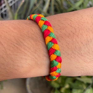 May include: A braided bracelet with red, yellow, and green stripes.