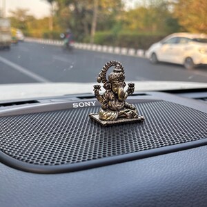 May include: A gold-colored metal figurine of the Hindu deity Ganesha, sitting on a small platform. The figurine is placed on a black speaker grill with the word "SONY" printed on it.