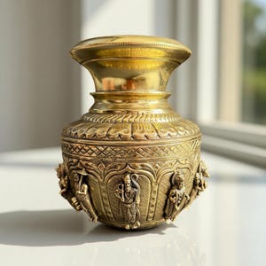 Puede incluir: Una detallada olla de latón con una base ancha y ornamentada y una parte superior acampanada. La olla presenta intrincadas tallas de figuras y patrones, mostrando un rico tono dorado. El diseño sugiere un artefacto cultural o religioso.