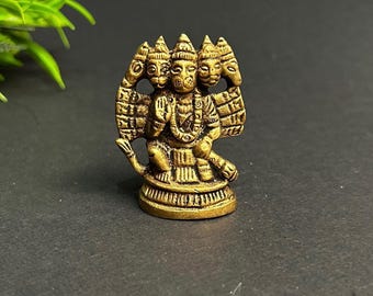 Könnte beinhalten: Eine kleine, goldfarbene Metallstatue einer vierköpfigen hinduistischen Gottheit. Die Gottheit sitzt mit gekreuzten Beinen und trägt eine Krone auf dem Kopf. Die Statue ist detailliert und kunstvoll.