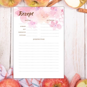 May include: A printable recipe template with a watercolour background featuring pink flowers. The template includes sections for the date, ingredients, and preparation instructions.