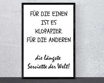 May include: A black framed print with white text that reads "FÜR DIE EINEN IST ES KLOPAPIER. FÜR DIE ANDEREN die längste Serviette der Welt!"