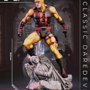 May include: A yellow and black Daredevil figure standing on a stone angel base. The figure wears a black tank top with a red D, red belt, and black boots. Text includes NICE X COLLECTIBLES, CLASSIC DAREDEVIL, and dimensions of 314.11 mm by 191.12 mm.