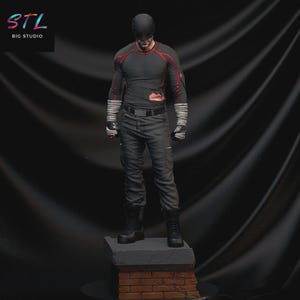 Peut inclure: Figurine d'un super-héros en costume noir et rouge, debout sur un socle en briques et en pierre. La figurine porte un masque, des gants et des bottes. Le texte "STL BIG STUDIO" est dans le coin supérieur gauche.