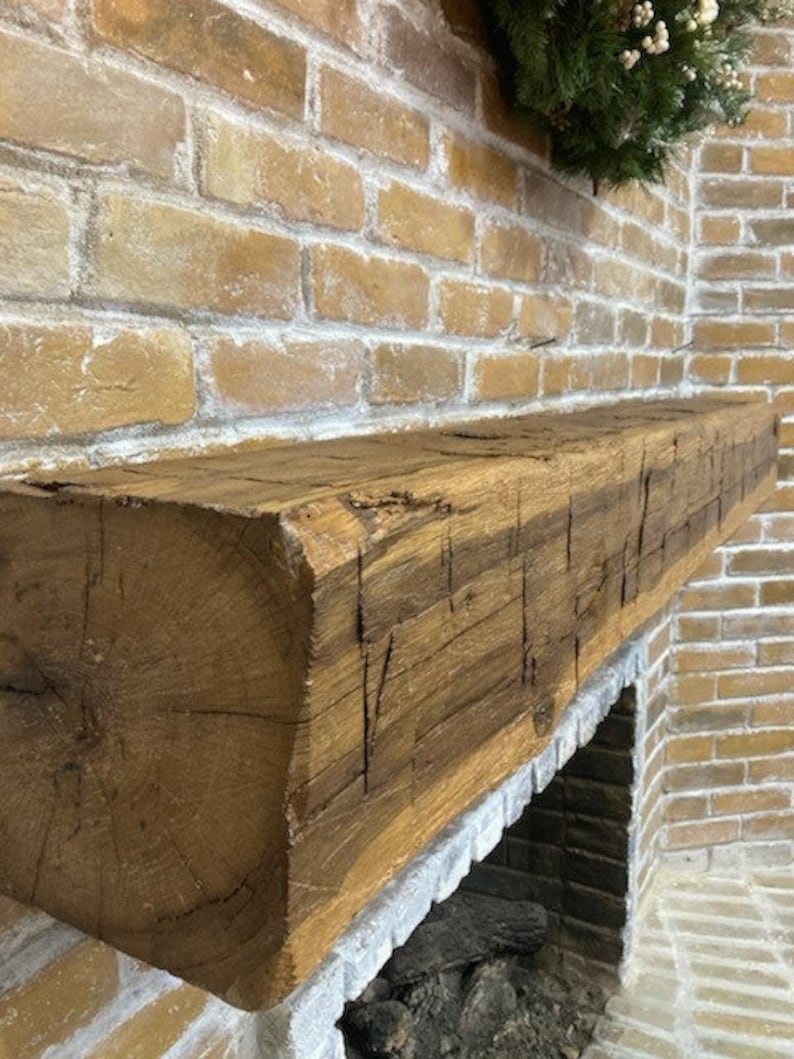 May include: A rustic wooden mantel made from reclaimed wood with a natural brown finish. The mantel is mounted above a brick fireplace.