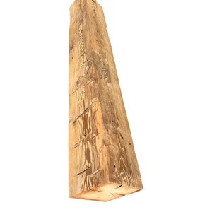 May include: A large, rough-hewn wooden beam with a natural, light brown color. The beam has a rectangular shape and shows signs of age and wear.