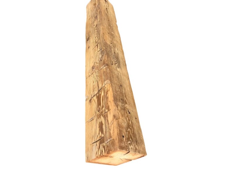 May include: A large, rough-hewn wooden beam with a natural, light brown color. The beam has a rectangular shape and shows signs of age and wear.