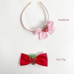 May include: A pink and white gingham bow headband and a red satin bow hair clip, both adorned with sequined strawberry embellishments. The headband is thin and delicate, while the hair clip is a classic bow shape.