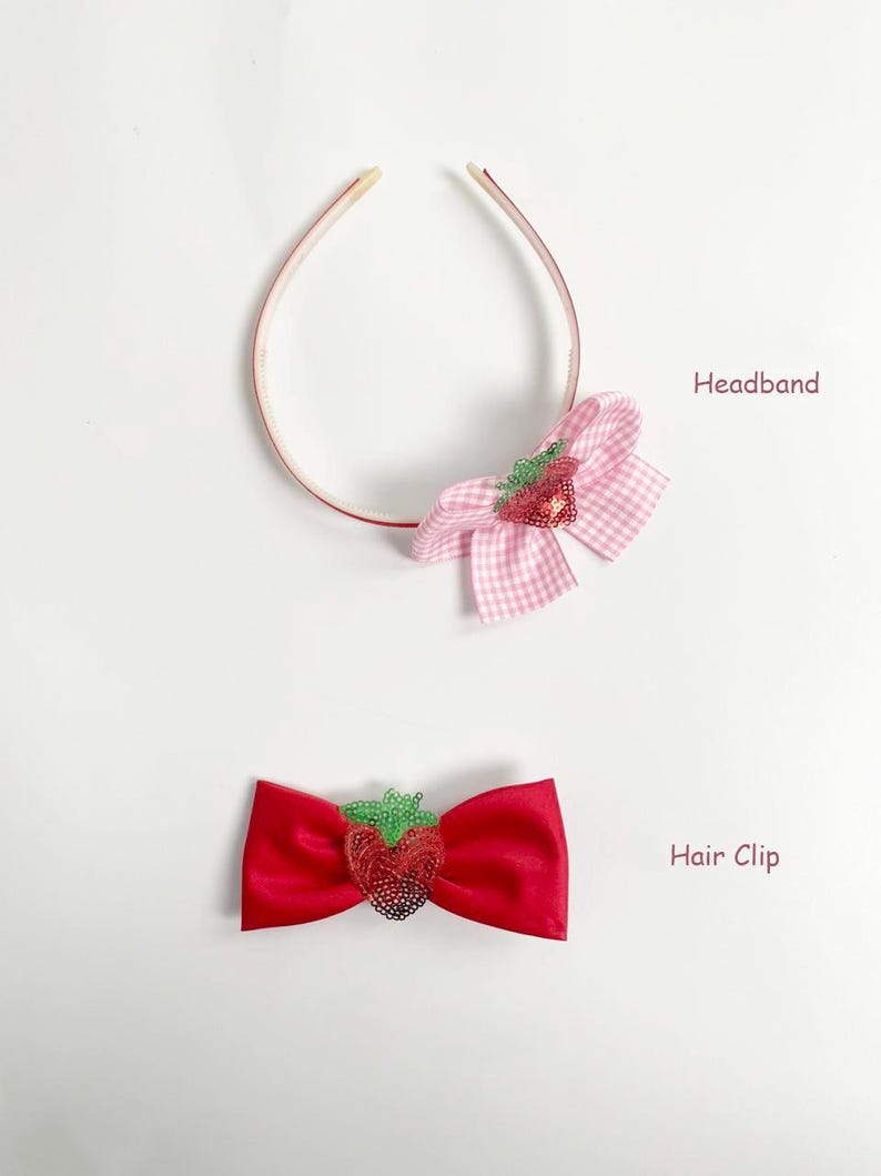 May include: A pink and white gingham bow headband and a red satin bow hair clip, both adorned with sequined strawberry embellishments. The headband is thin and delicate, while the hair clip is a classic bow shape.