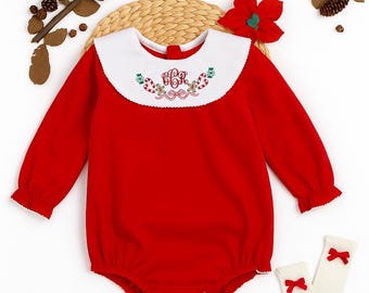 May include: A red baby romper with a white collar featuring embroidered Christmas-themed details. The long-sleeved romper has a round collar and snap closures. A pair of white socks with red bows are also included.