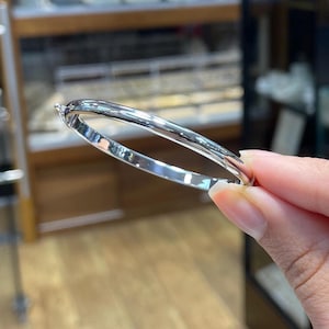 May include: A silver bangle bracelet with a smooth, polished finish.