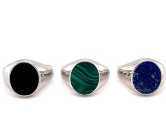 May include: Three silver signet rings with oval shaped gemstones. The rings feature a black onyx, a green malachite, and a blue lapis lazuli.